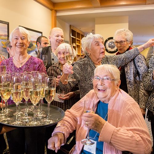 A group of senior residents gathered for a celebration toast of champagne at Origin at Spring Creek