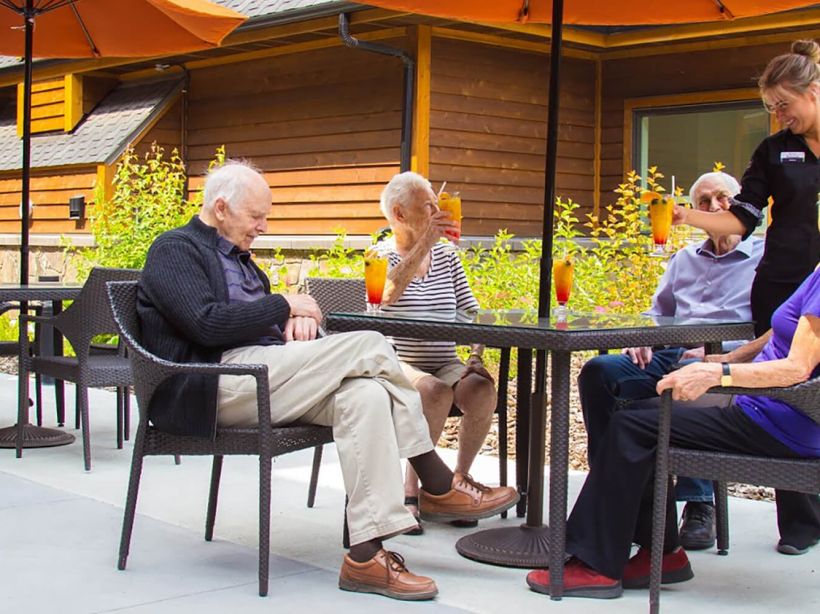 Three seniors sit on a patio at the Mineshaft Tavern at Origin at Spring Creek in Canmore, Alberta