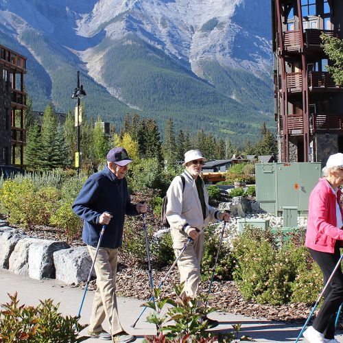Three seniors with walking sticks on a walking path at Spring Creek in Canmore, Alberta