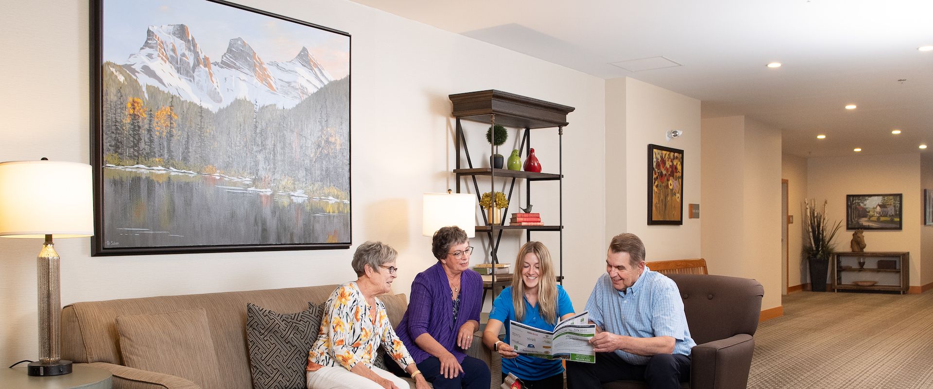 Three senior residents and a younger adult companion chat in a comfortable living space at Origin at Spring Creek.