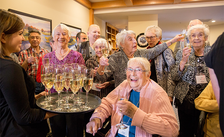 A group of senior residents gathered for a celebration toast of champagne at Origin at Spring Creek