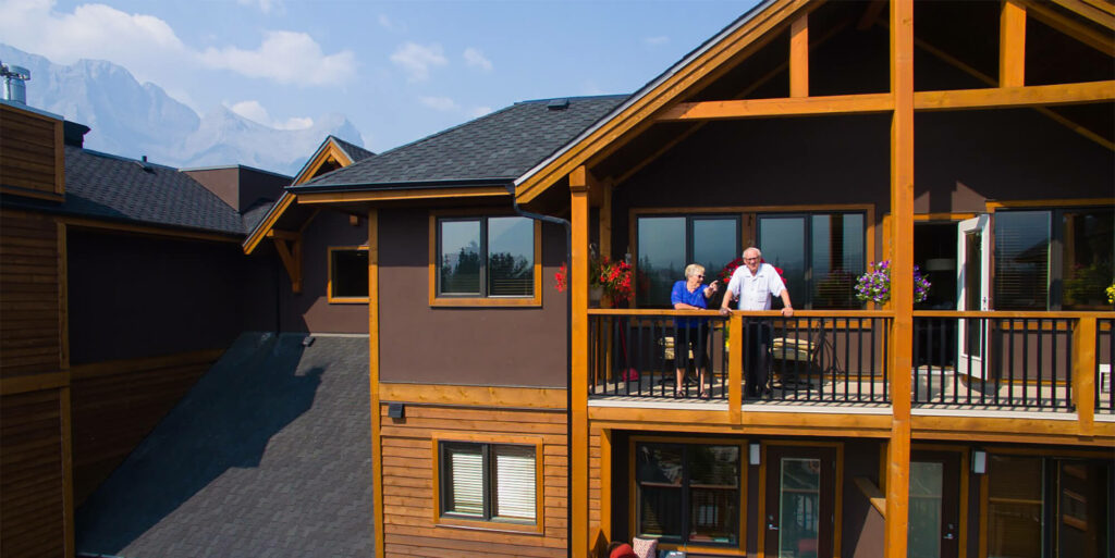 Two seniors stand on the balcony of a suite at Origin at Spring Creek